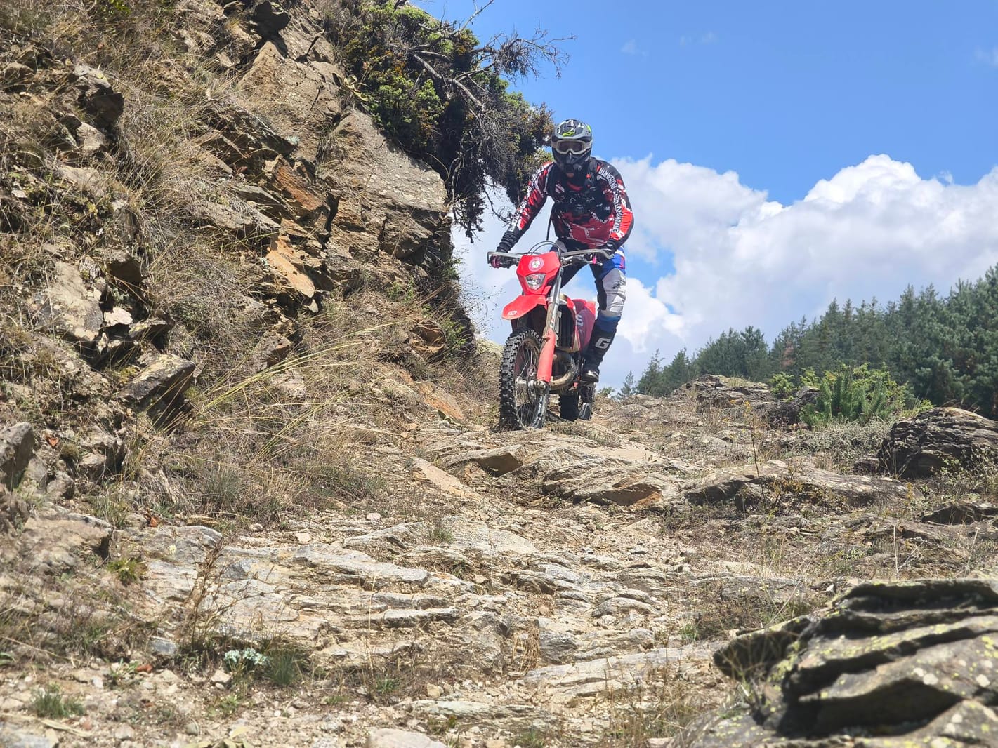 Enduro group riding a ridge traverse in the Pirin Mountains with three-thousand-metre peaks behind
