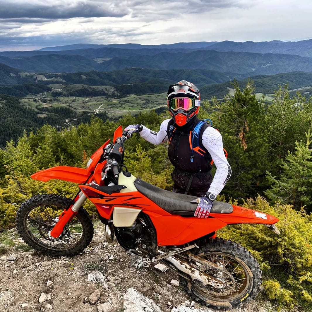 Road rider on a first enduro day, standing on the pegs through a forestry corner in the Pirin foothills